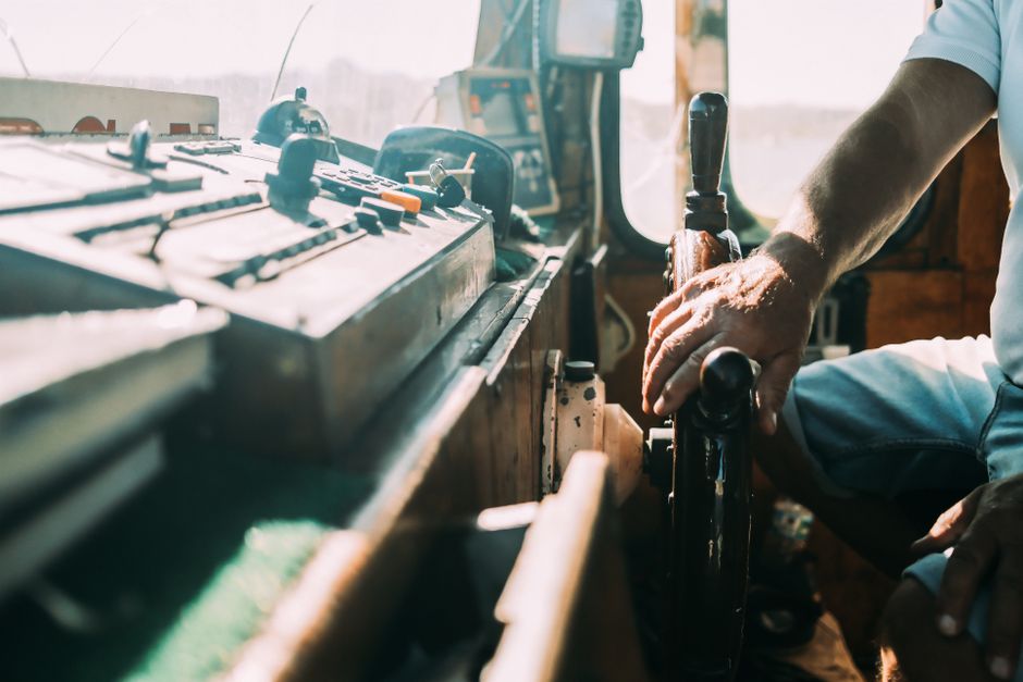 Professional charter boat captain stands thoughtfully at the helm of his boat during a golden sunrise, planning his next m...